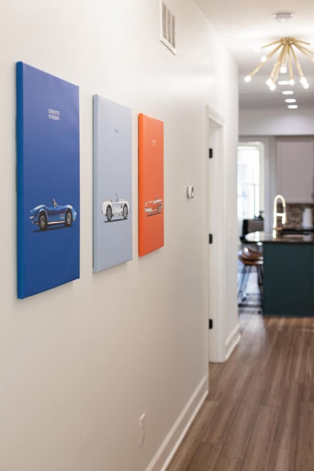 Stylish hallway with vibrant car-themed artwork, leading to a modern kitchen and cozy living space. 