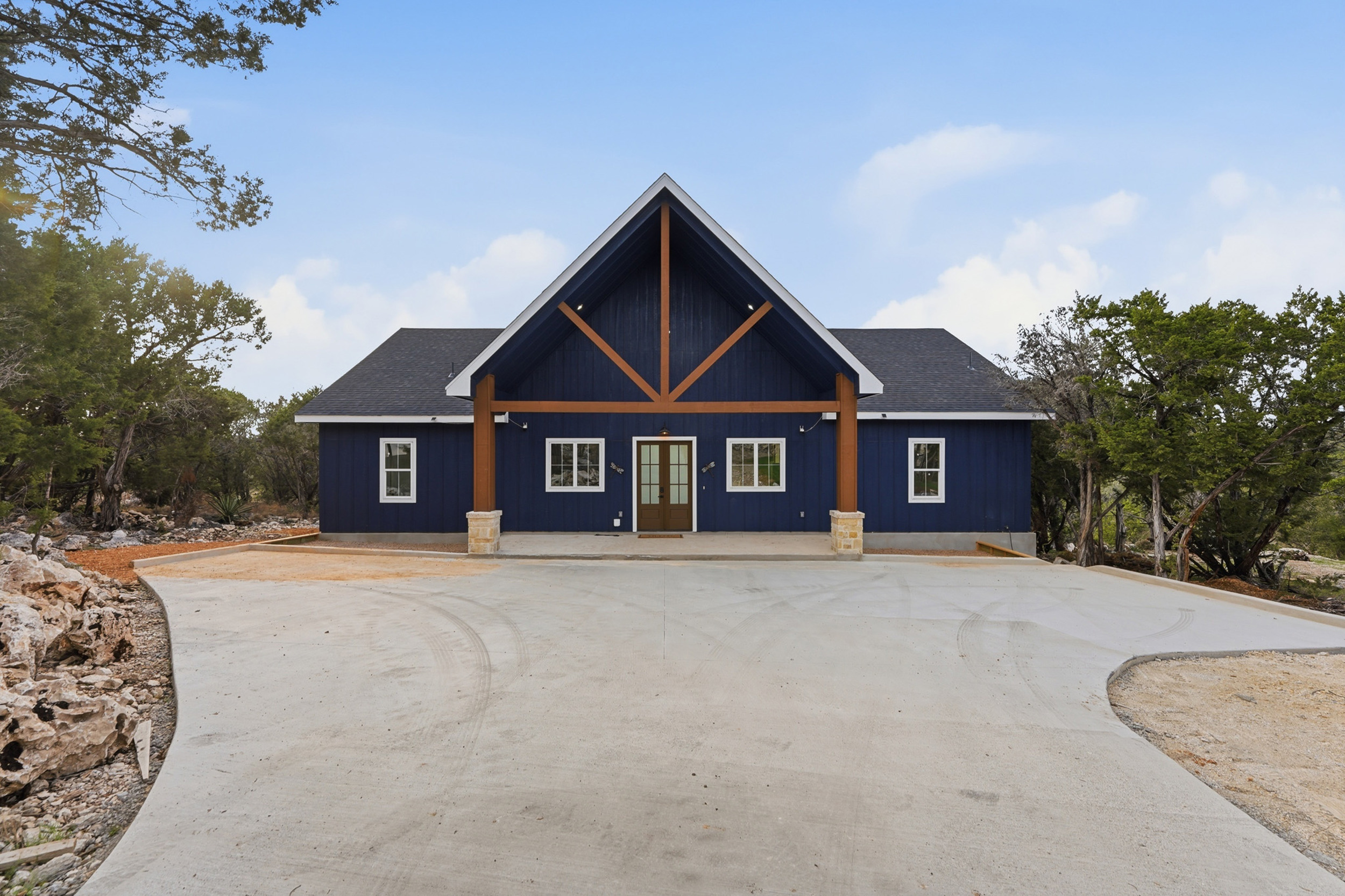 Welcoming front elevation surrounded by mature trees.
