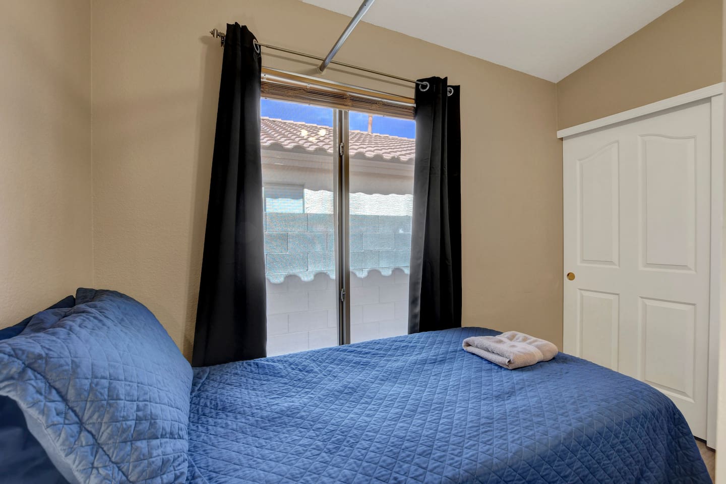 Cozy bedroom with patio access, navy bedding, and closet storage