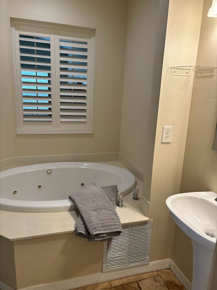 Bathroom featuring a relaxing soaking tub, pedestal sink, and bright natural light.