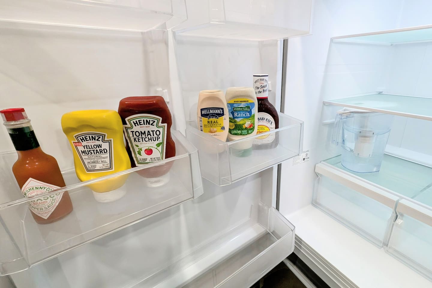 Fridge is stocked with a filtered water jug and condiments for guest use. 