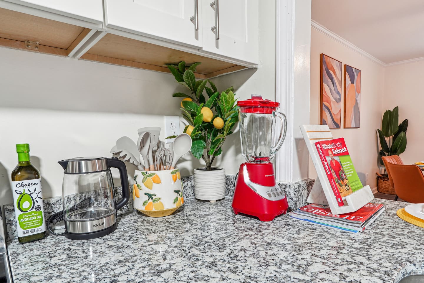 A fully equipped kitchen with a refrigerator, microwave, stove, oven,fridge, dishwasher, coffee maker, kettle, toaster, and blender. Includes plates, bowls, utensils, pots, and pans, plus four bar chairs for casual dining or socializing.
