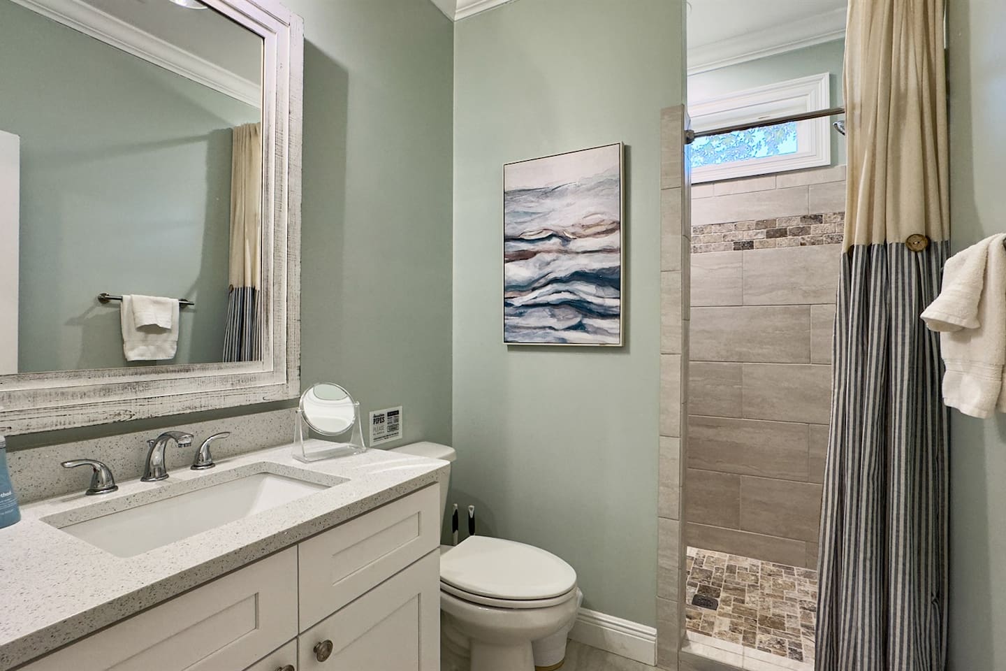 Bright bathroom with a walk-in shower, clean vanity, and soothing coastal accents.