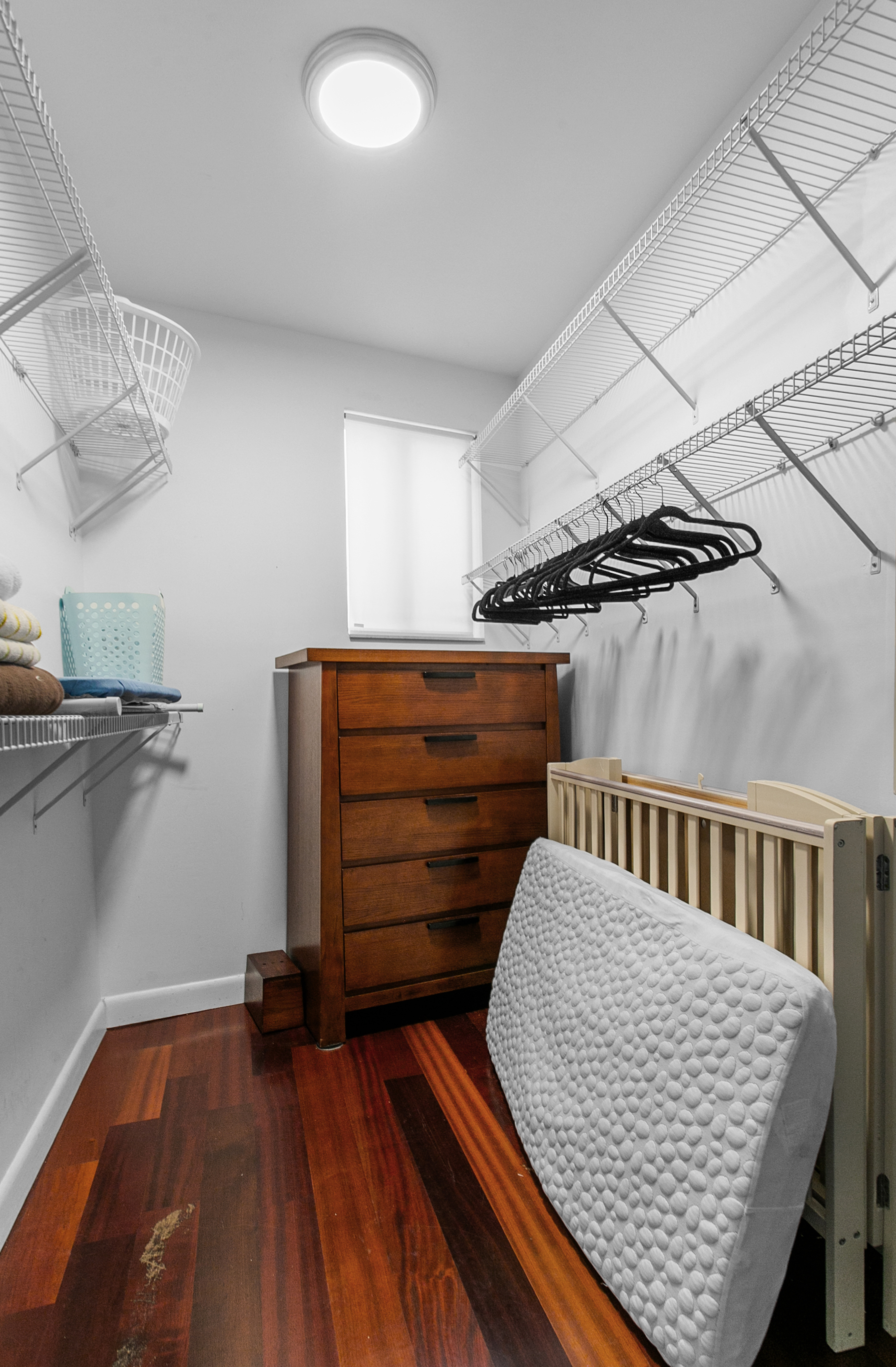 Primary walk in closet with storage and full size crib