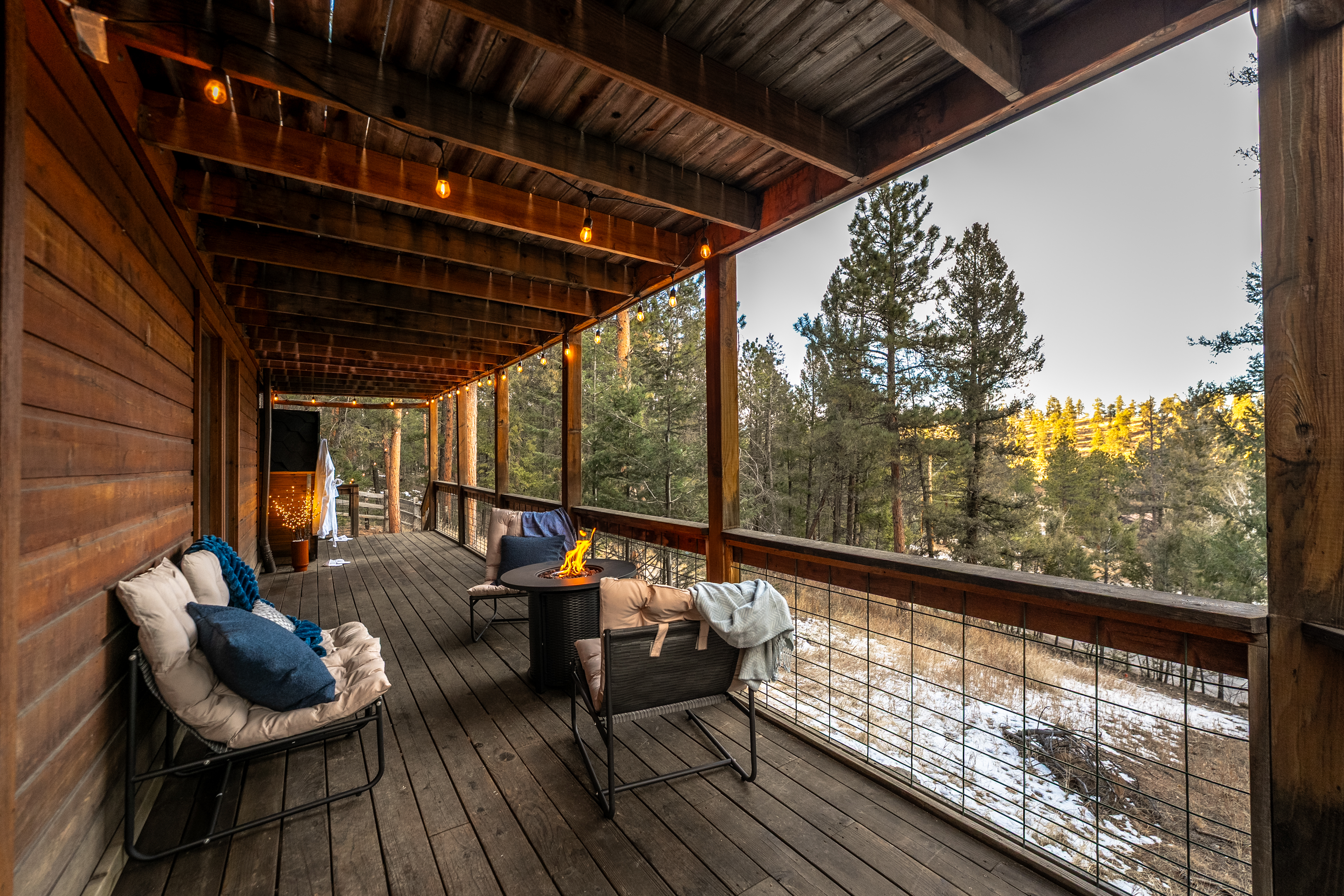 ✨🔥 Stretch out on the covered deck under string lights—cozy lounge seating, a glowing fire table, and sweeping pine views for the ultimate mountain chill 🌲🌄