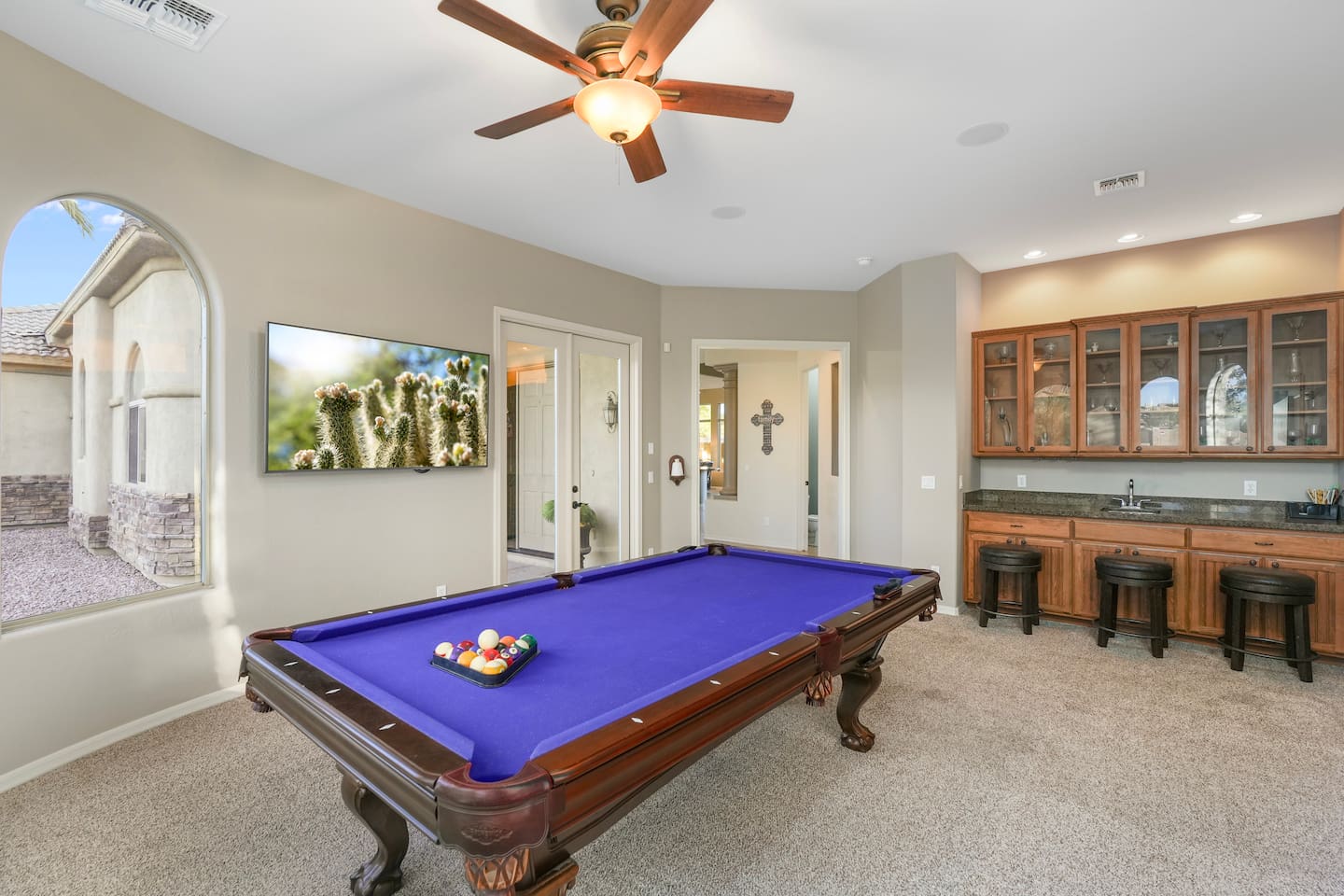Spacious game room featuring a full-size pool table, ceiling fan, and plush carpeting.