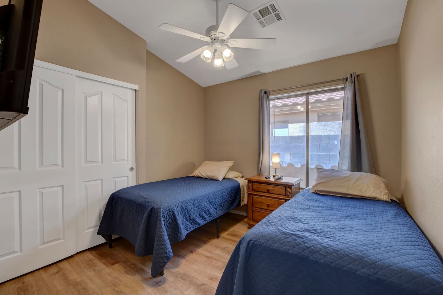 Cozy twin-bedroom with fan, closet, and bright window—great for kids.