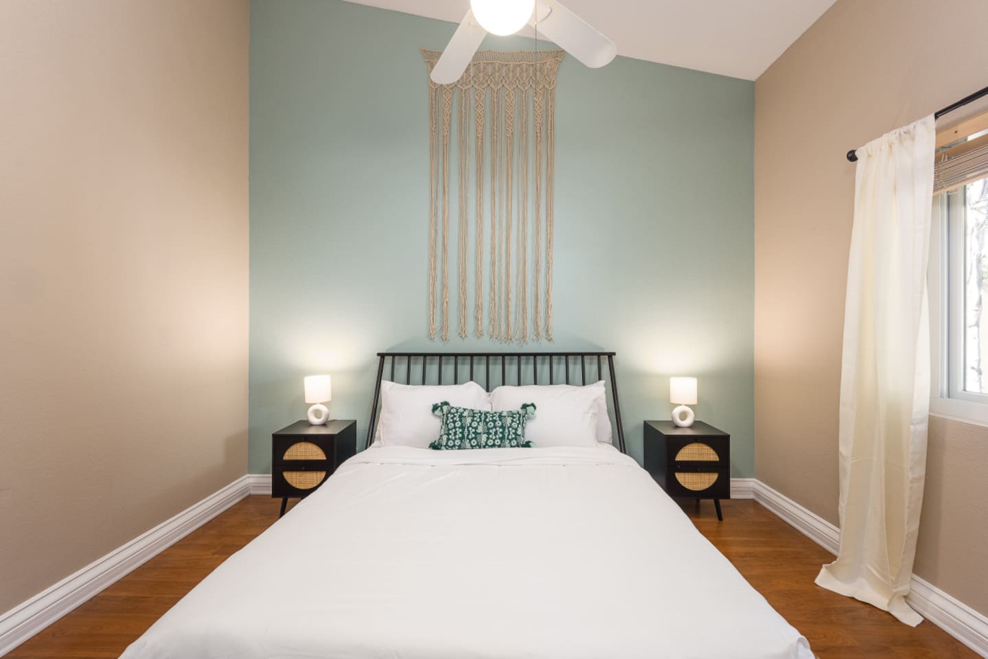 Guest bedroom with a queen bed, ceiling fan, bedside lighting, and a calm accent wall for a restful stay.