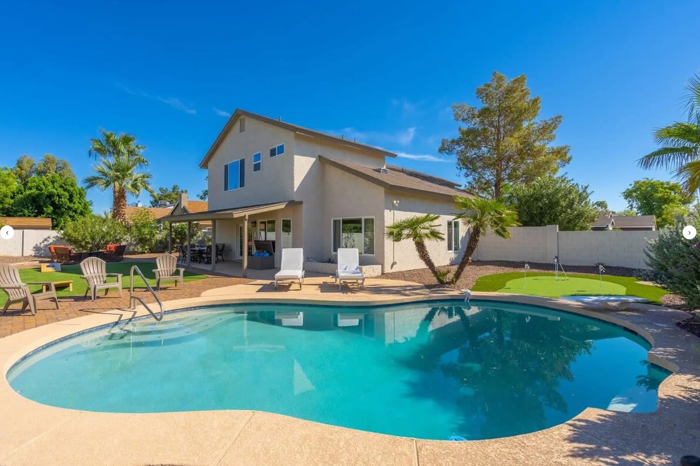 Modern home with sparkling freeform pool, mature landscaping, and open-concept patio living.