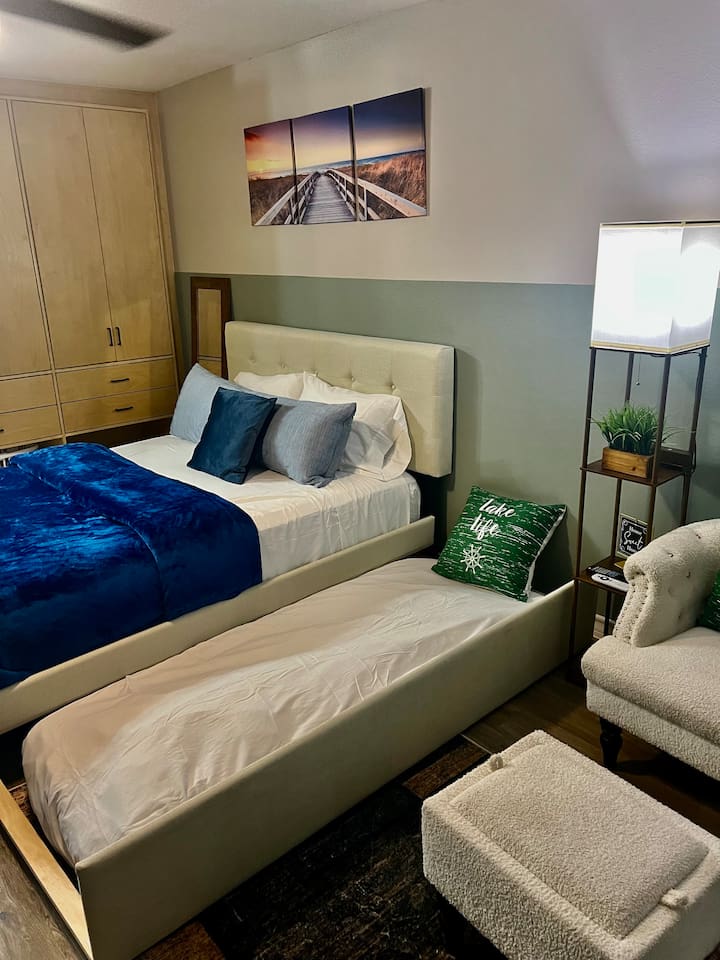 Queen bed with a twin pull-out underneath, plus a chair and ottoman for relaxing.
