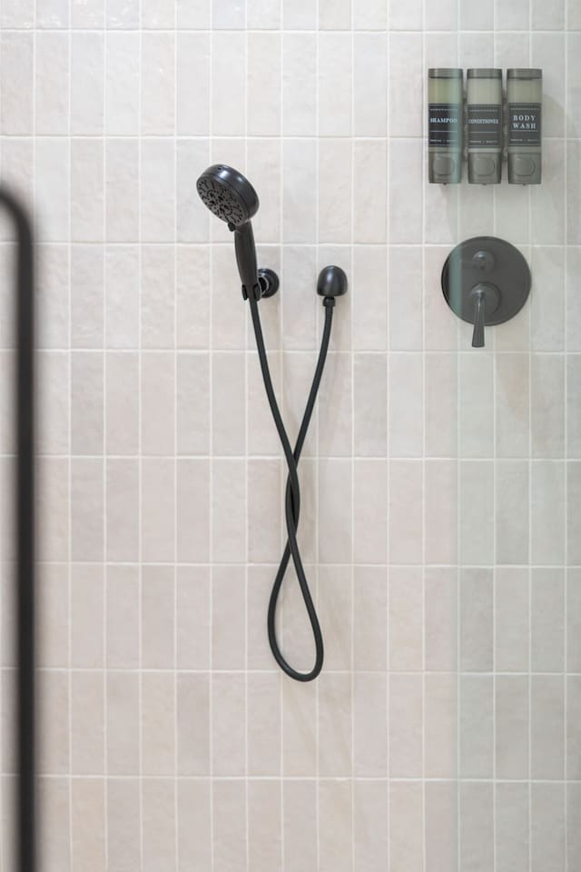 Handheld shower with mounted shampoo, conditioner, and body wash dispensers.