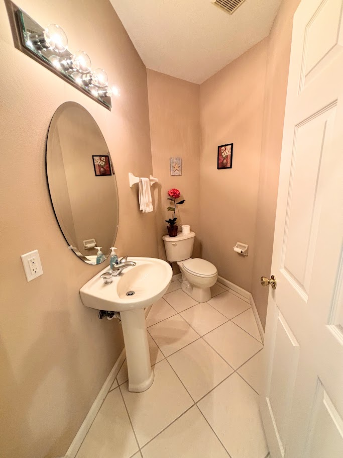 Convenient half bathroom with pedestal sink, tile flooring, and clean neutral finishes.