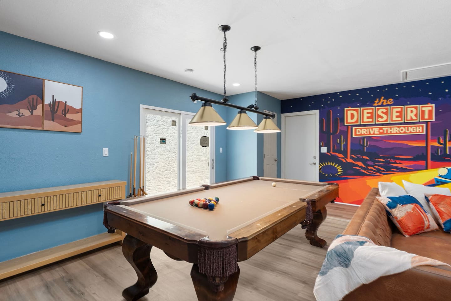 Entertainment lounge with pool table, vintage desert mural, blue walls, and seating—a fun, laid-back hangout for guests.