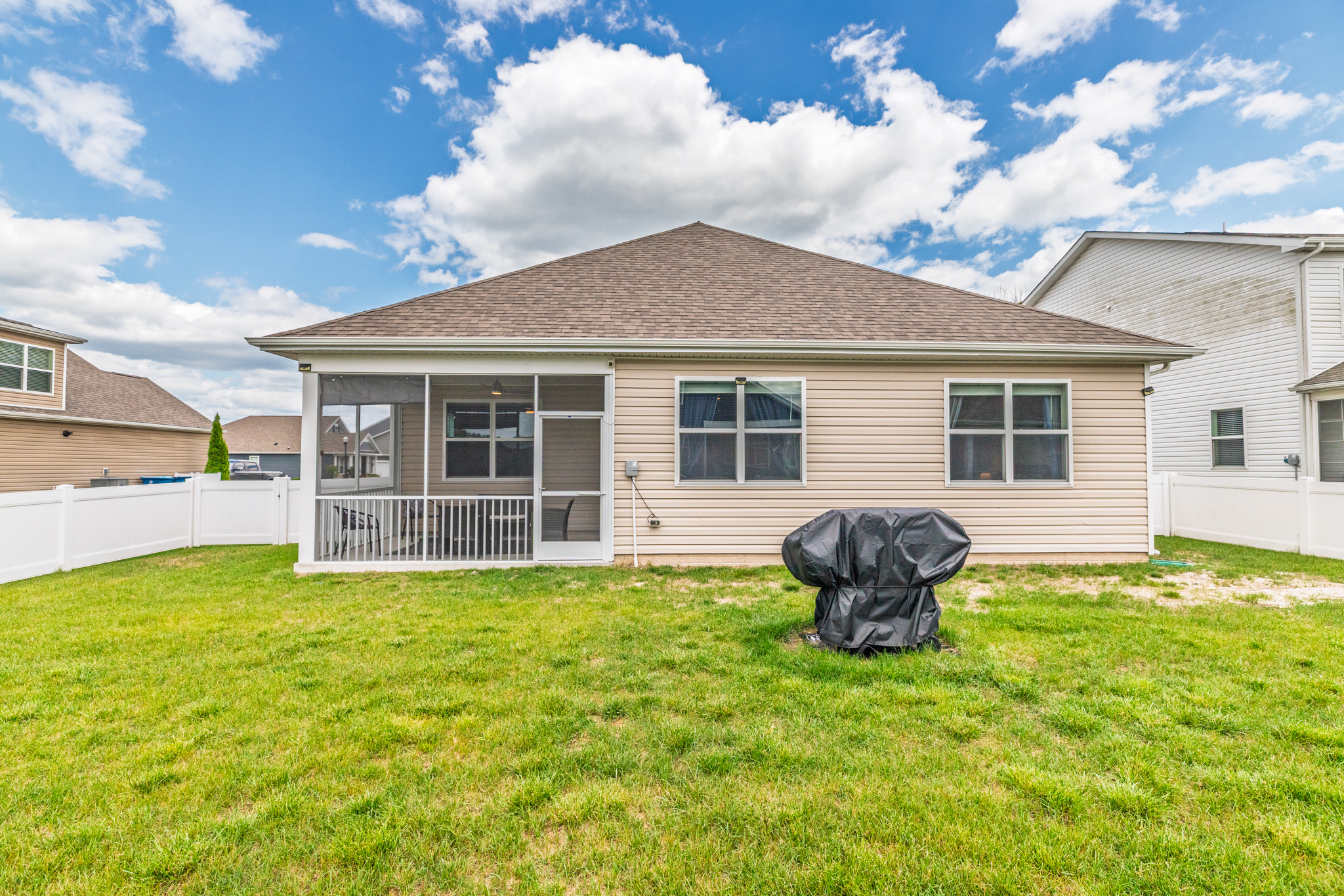 A wide-angle shot captures the lush green lawn and crisp white vinyl fence, showcasing plenty of open space for kids’ games, sunbathing, or setting up yard activities.
