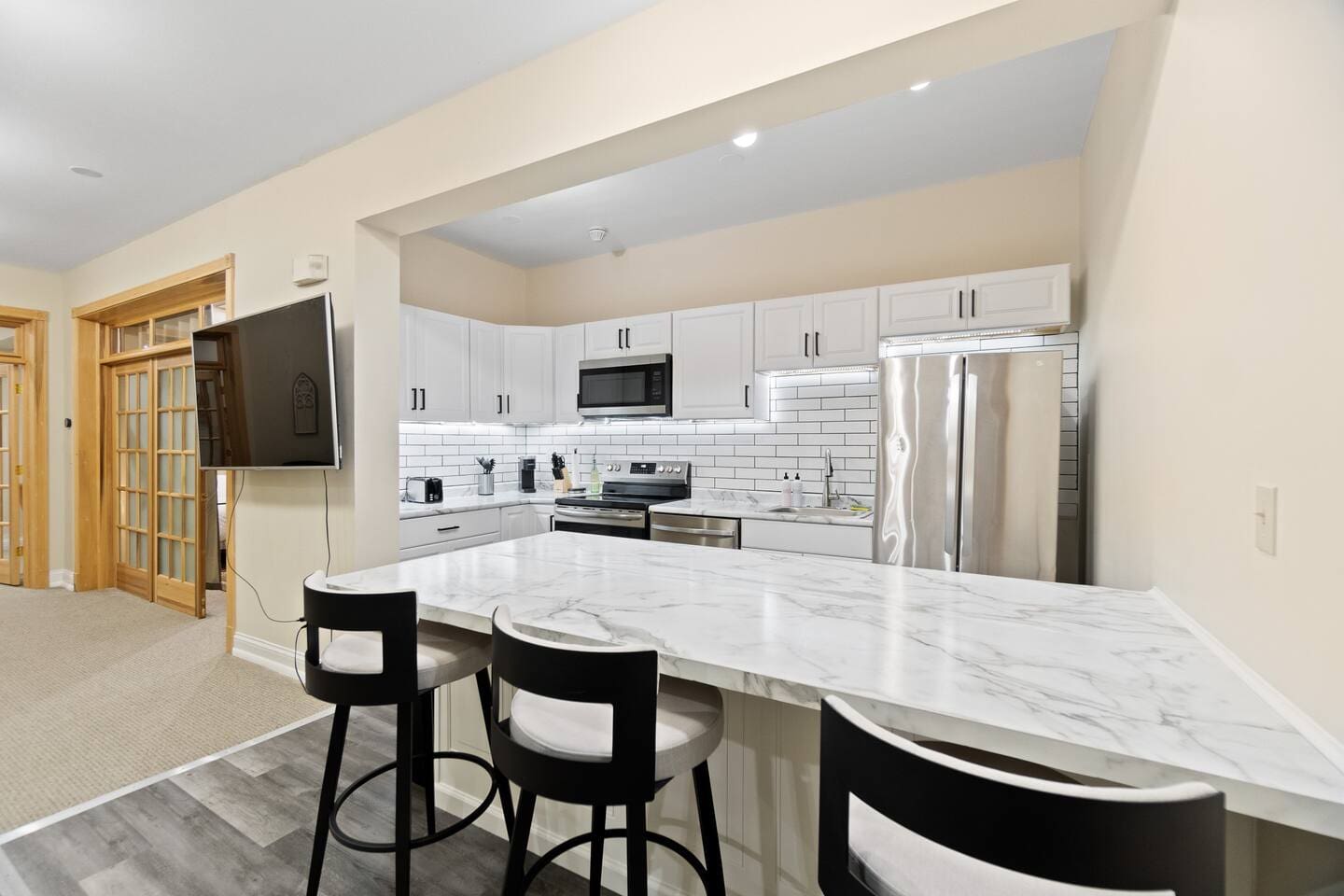 Kitchen counter with seating for three, offering a great view of both the kitchen and the living area’s TV, perfect for casual dining and socializing.