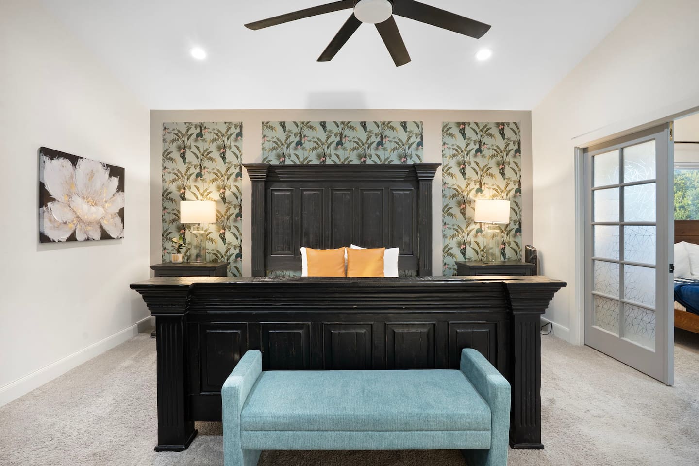 Stunning master suite with statement black bed frame, botanical wallpaper accent wall, and spa-like ensuite.