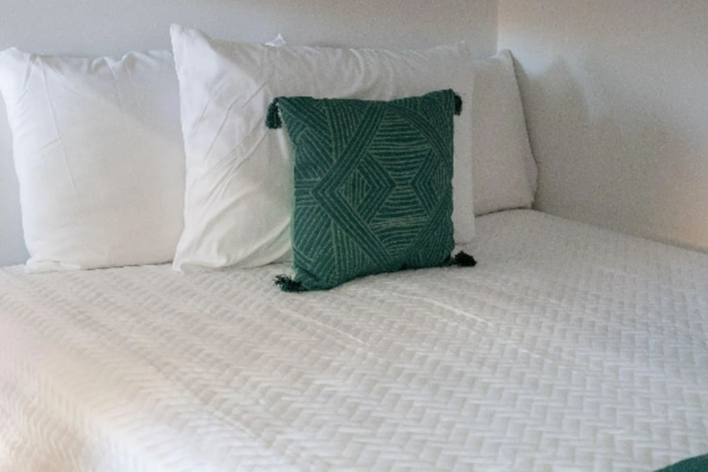 Crisp white linens get a pop of personality from a hand-woven, tasseled accent pillow, keeping the space playful without losing that put-together feel.