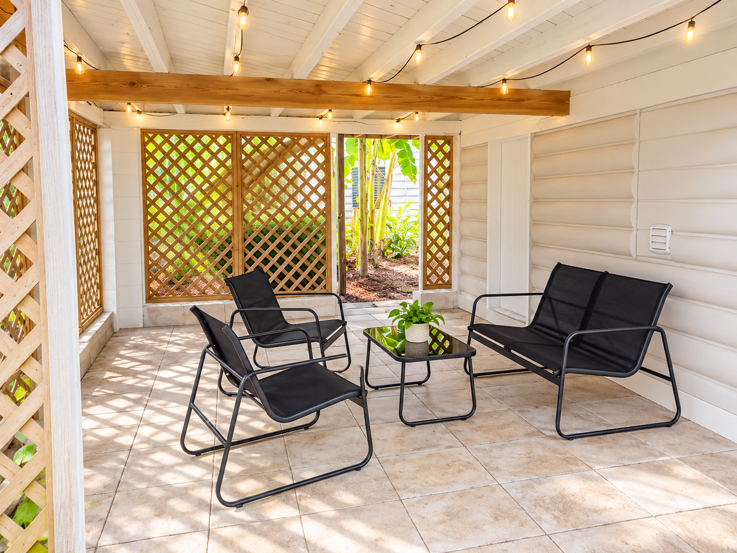 Covered patio with string lights, lattice walls, and cozy seating for gatherings.