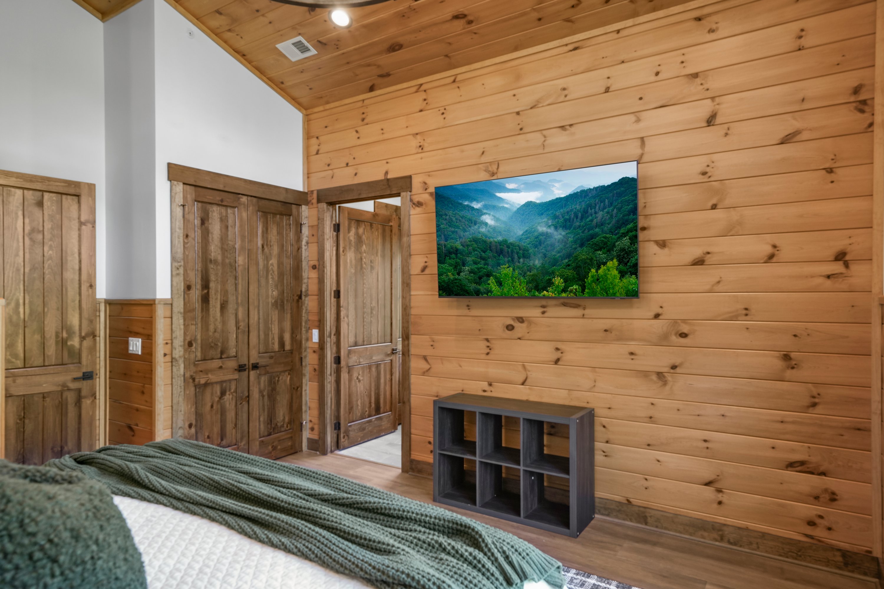 King Suite with vaulted ceilings an x-large TV. Unwind in the en-suite bathroom featuring a luxurious walk-in shower with a natural river rock floor, bringing  the Smoky Mountains indoors for a spa retreat.