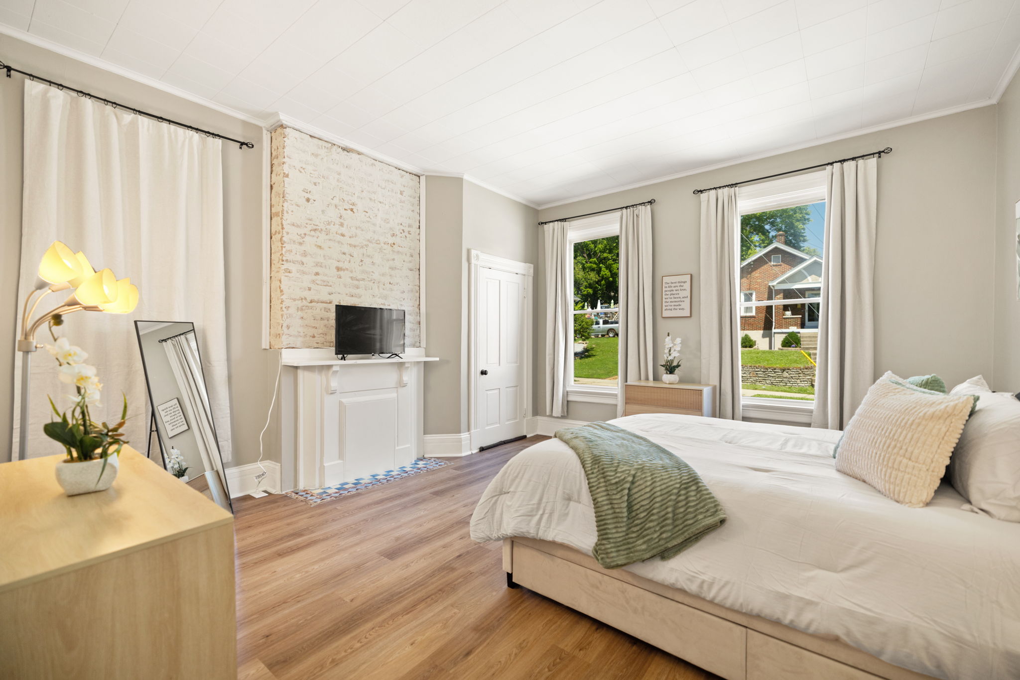 Spacious and serene bedroom bathed in natural light with large windows.