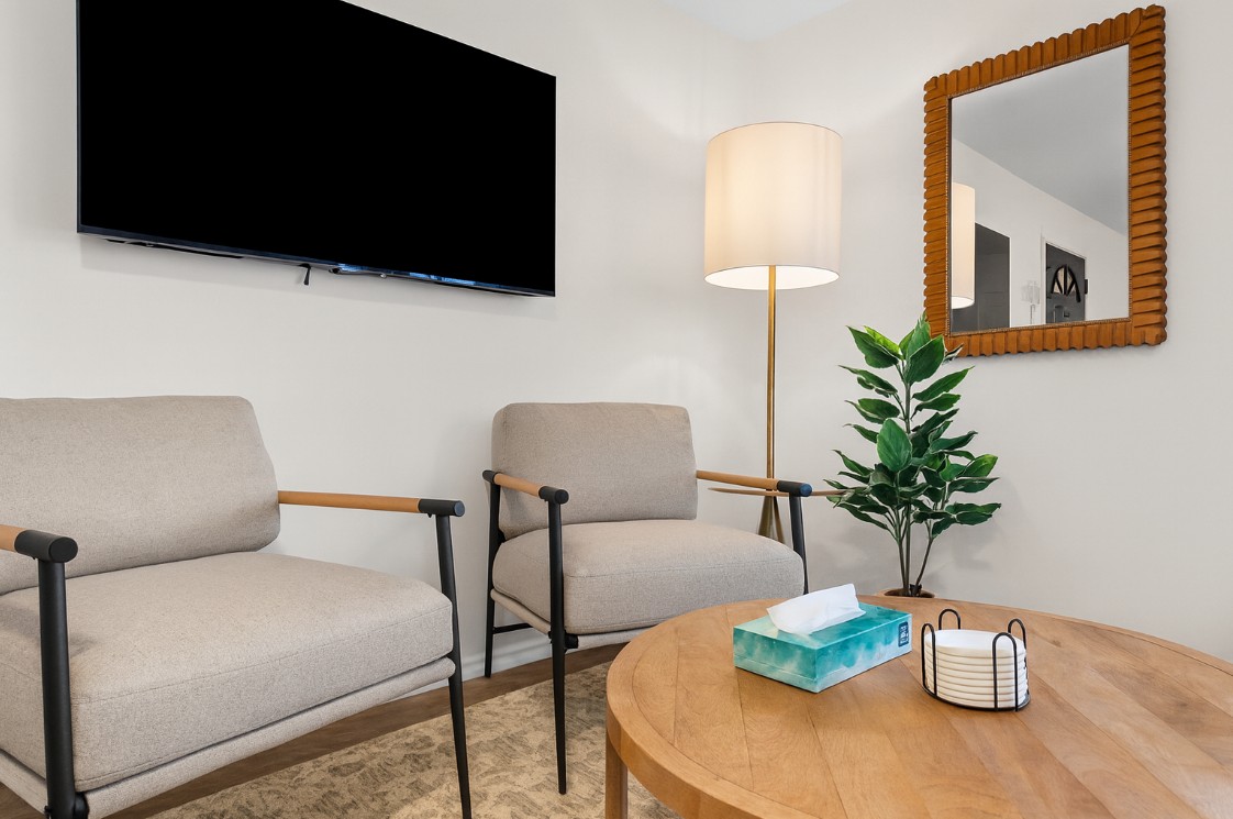 Cozy sitting area with modern armchairs, smart TV, and warm lighting—perfect for relaxing with a cup of coffee or unwinding after a day out.