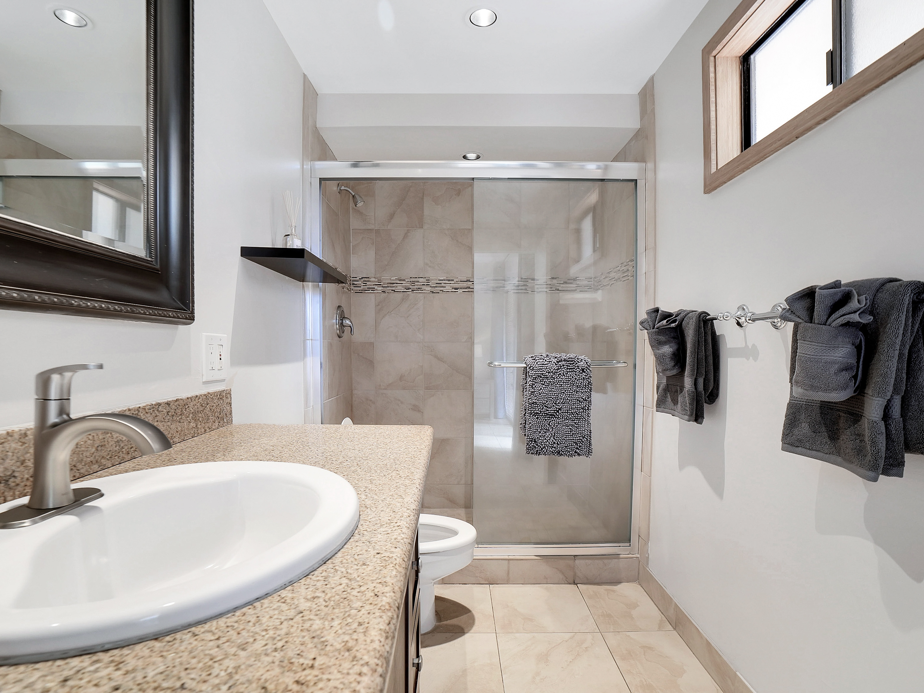 Bright, modern primary bathroom with a walk-in tile and glass shower