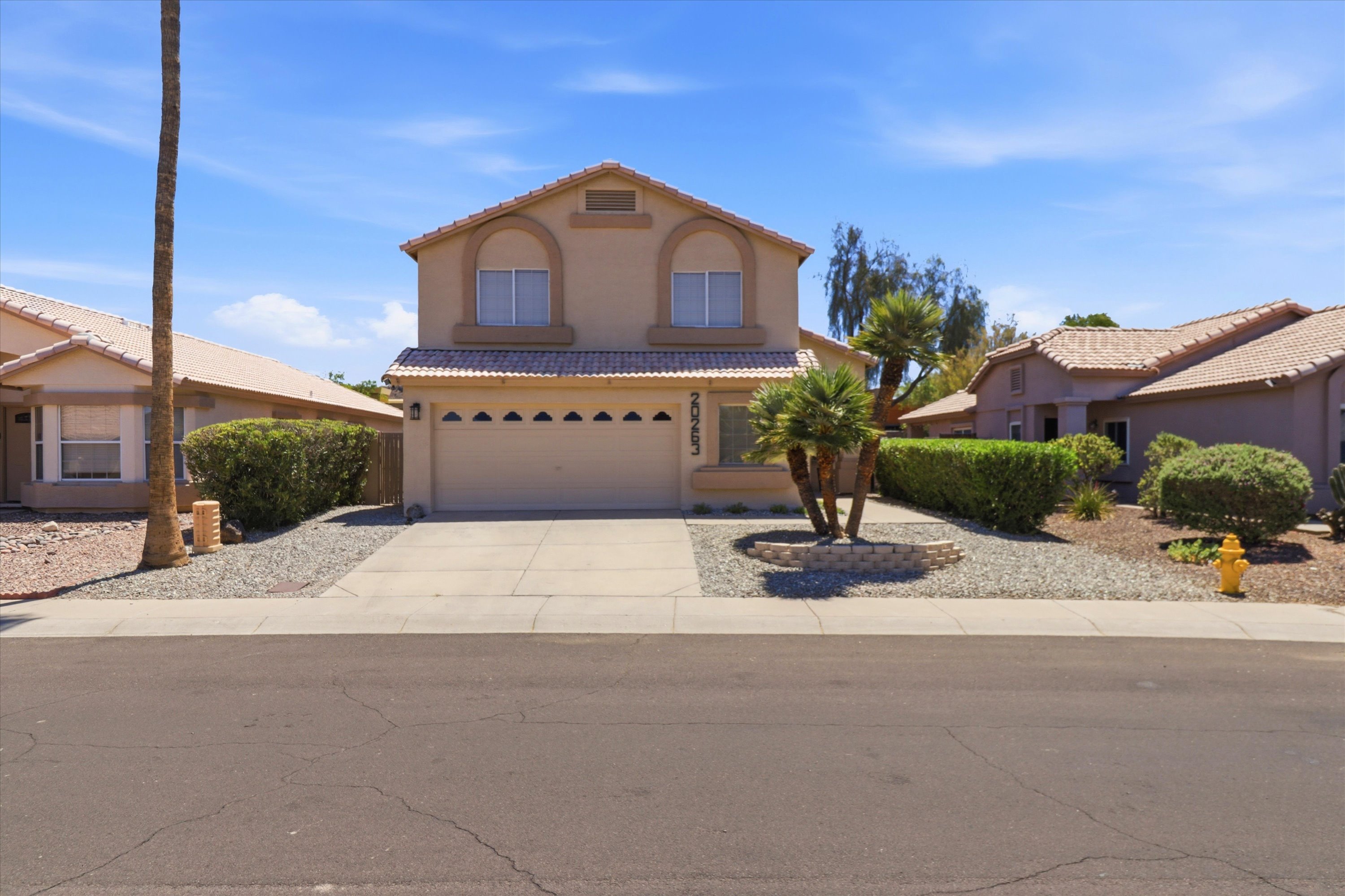 Front exterior with garage, driveway parking, desert landscaping, and a clean neighborhood arrival view.
