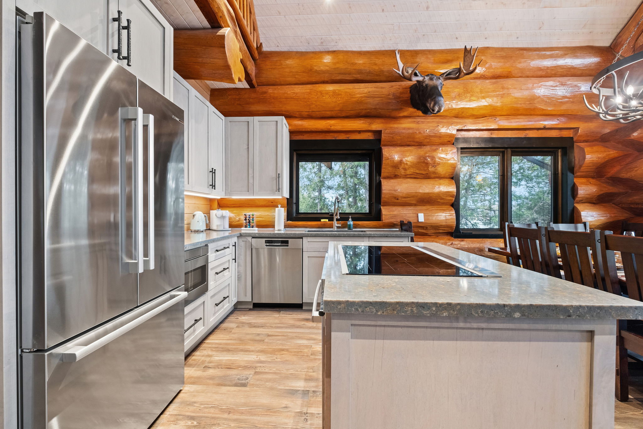Bright kitchen area with large fridge, spacious island, and forest-themed décor.