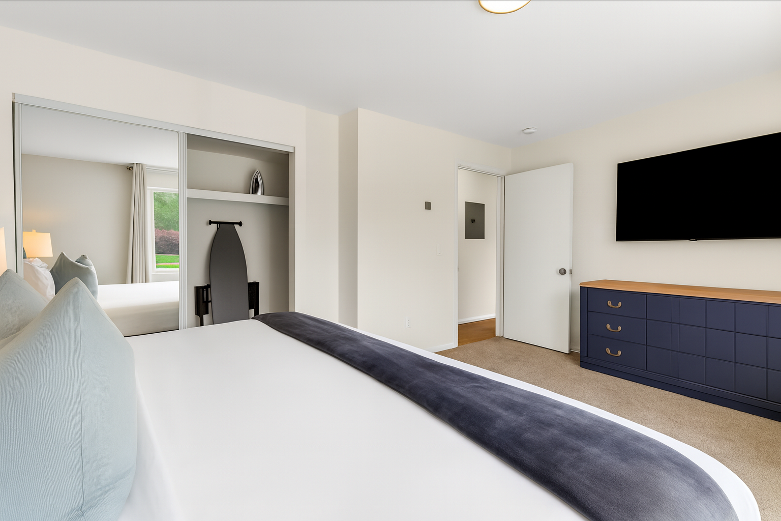 Spacious bedroom with Smart TV, dresser, and plenty of natural light for your comfort.