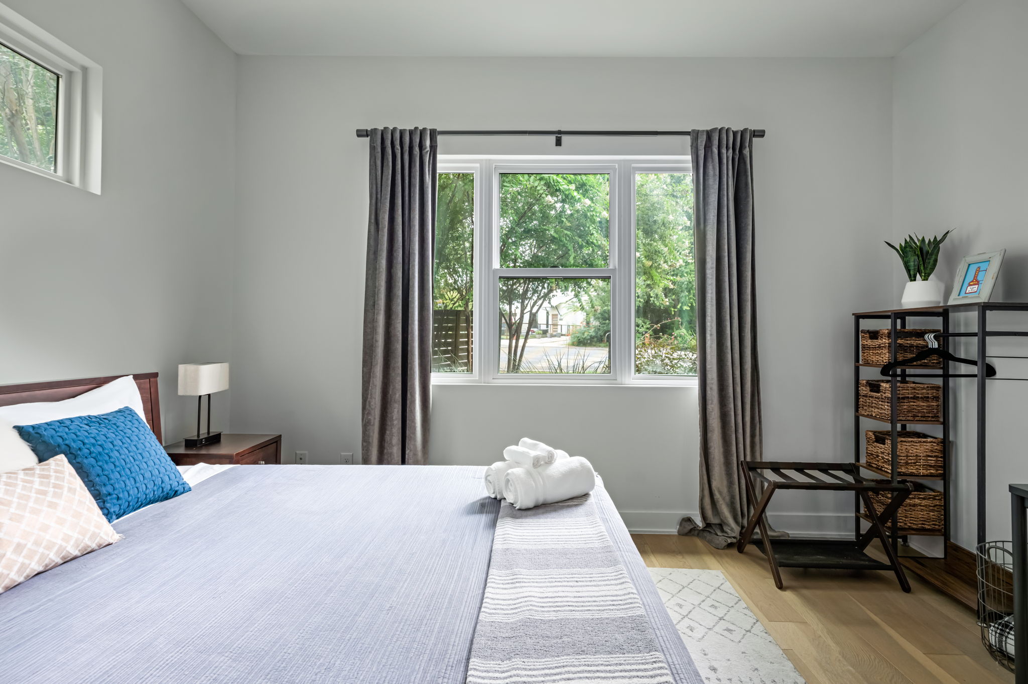 Airy guest bedroom with a crisp white and blue color palette, large windows, and a stylish workspace corner.