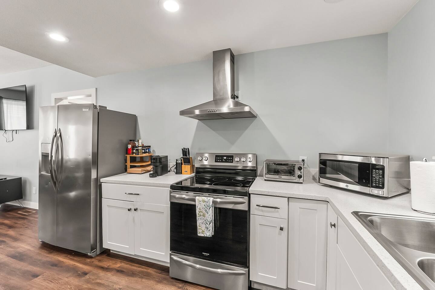 Sleek kitchen setup featuring a full-size refrigerator, electric range with stainless hood, and ample counter space.