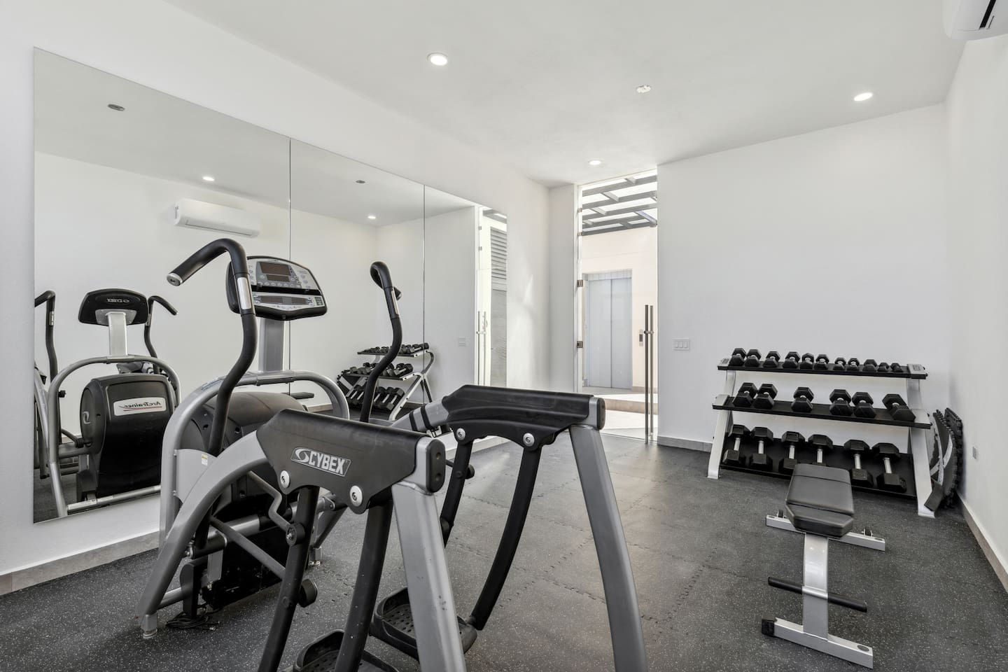 Stay fit in this modern Cabo gym, equipped with a treadmill, weight bench, and dumbbells, plus a mirrored wall for form checks. Perfect for maintaining your workout routine during your Mexico getaway.