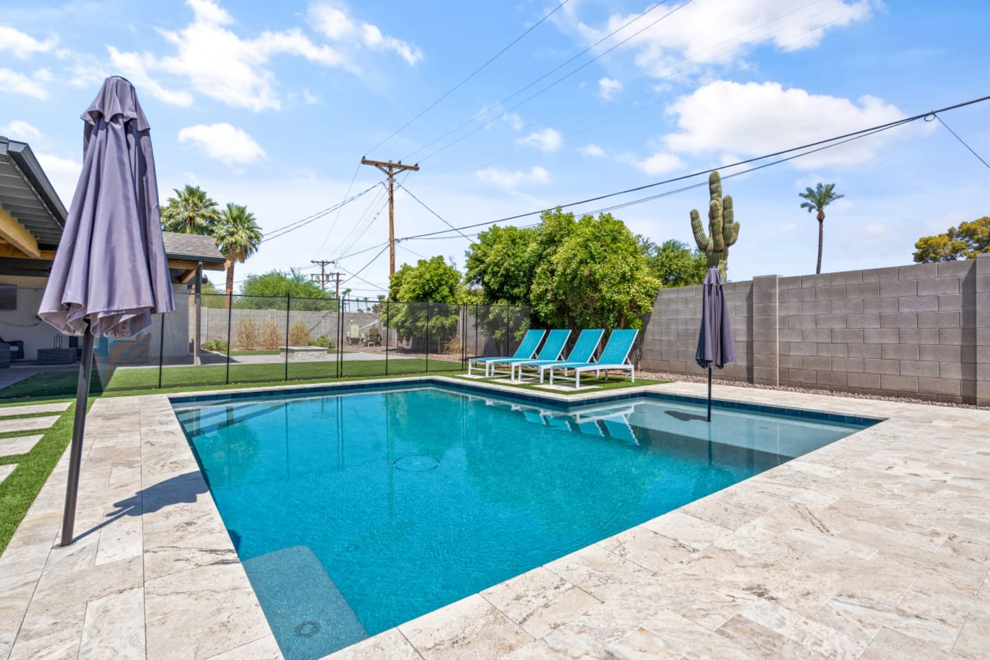 Private backyard pool with lounge chairs, umbrella shade, fire pit seating, and a bright outdoor space 