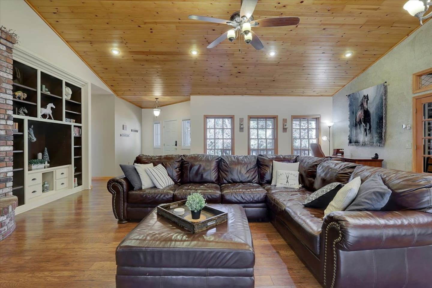Living room with leather sectional seating, wood ceilings, and room for everyone to gather.

