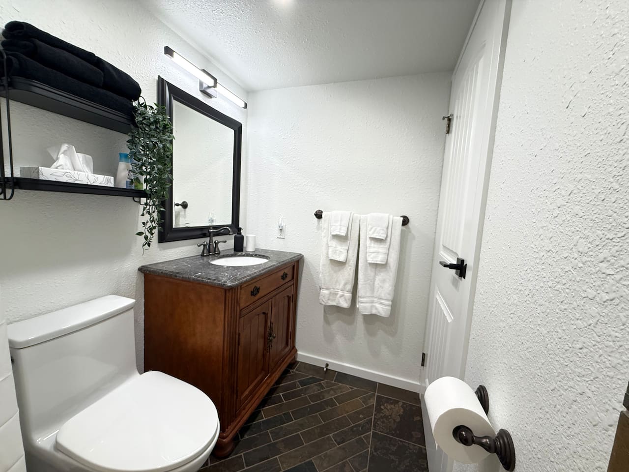Main Floor Bathroom: Features a new comfort-height toilet and a charming wood vanity with storage shelves for personal items.