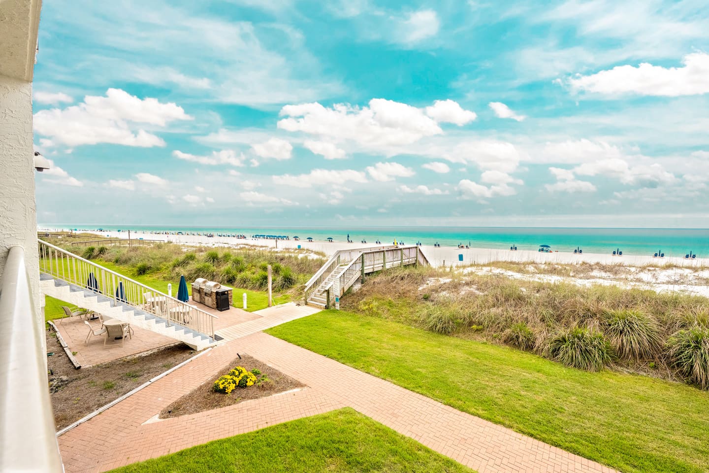 View toward Destin Beach and the Gulf, with shared beachfront grills and the building’s beach boardwalk.