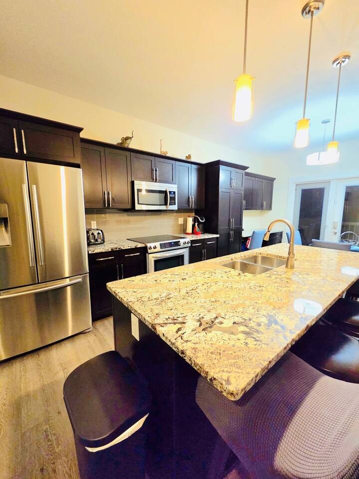 Stylish kitchen with granite island, SS appliances, and bar seating.