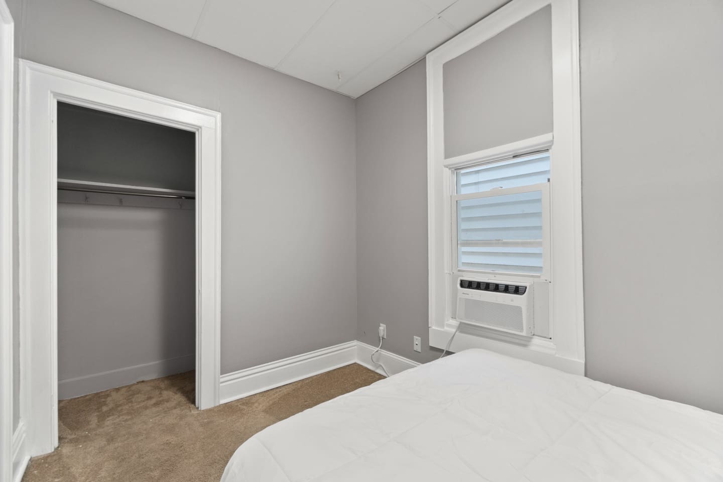 Bedroom with an open closet and window AC unit.