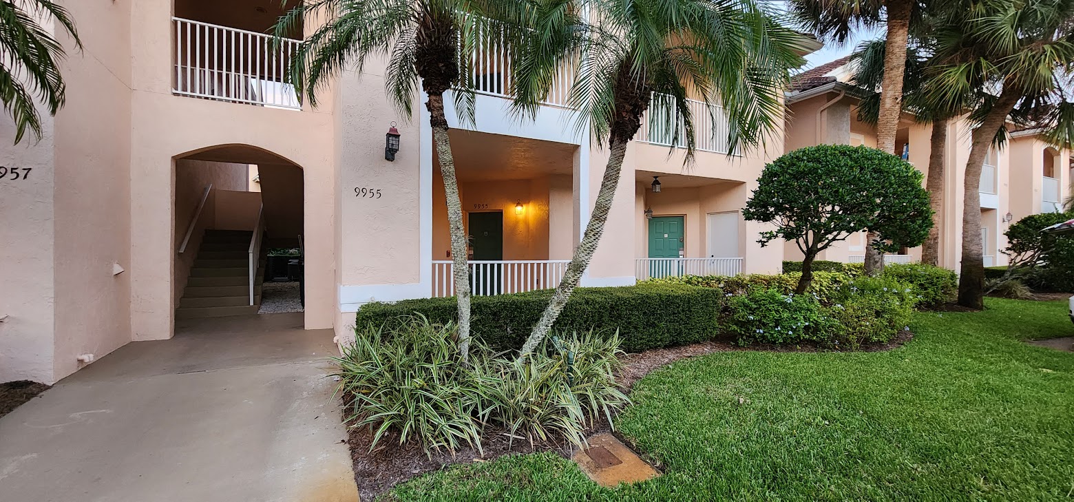 Exterior view of the building with tropical landscaping, covered entryway, and well-maintained grounds.
