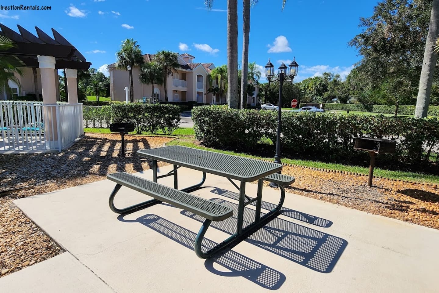 Outdoor picnic area with shaded seating and landscaped surroundings near the community pool.