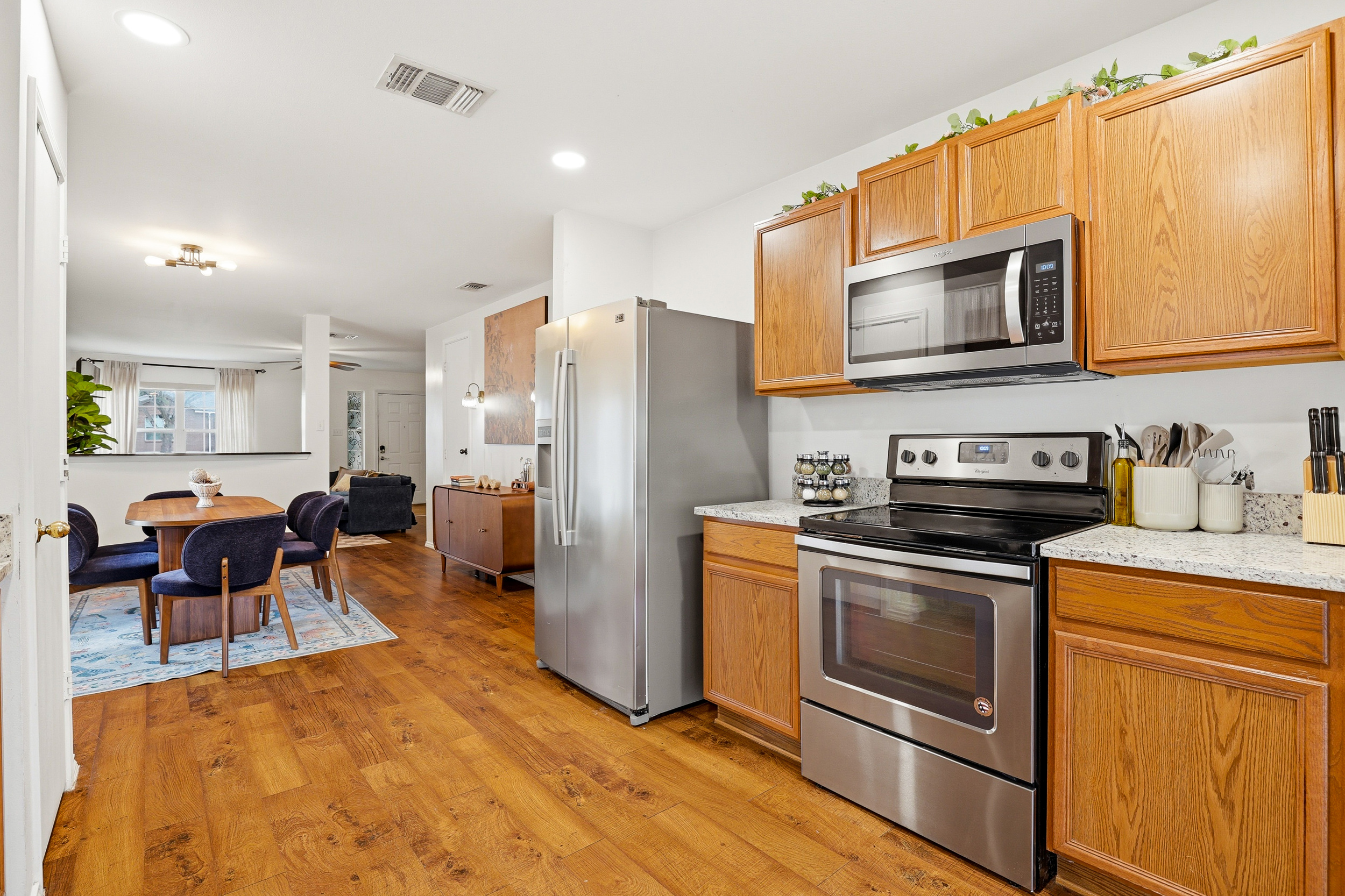 Fully equipped kitchen with electric stove, stainless dishwasher, granite countertops, ample cabinet storage, and sliding glass door to the backyard patio. Everything you need for home-cooked meals.