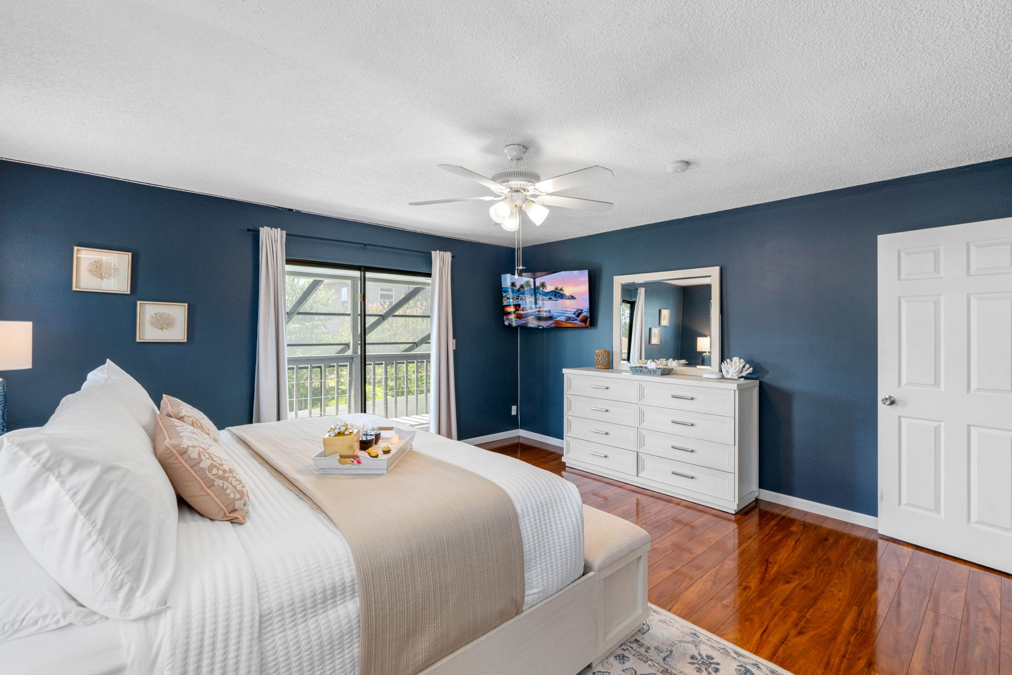 Unwind in this elegant bedroom where deep blue walls and soft lighting create a cozy, tranquil environment perfect for recharging.