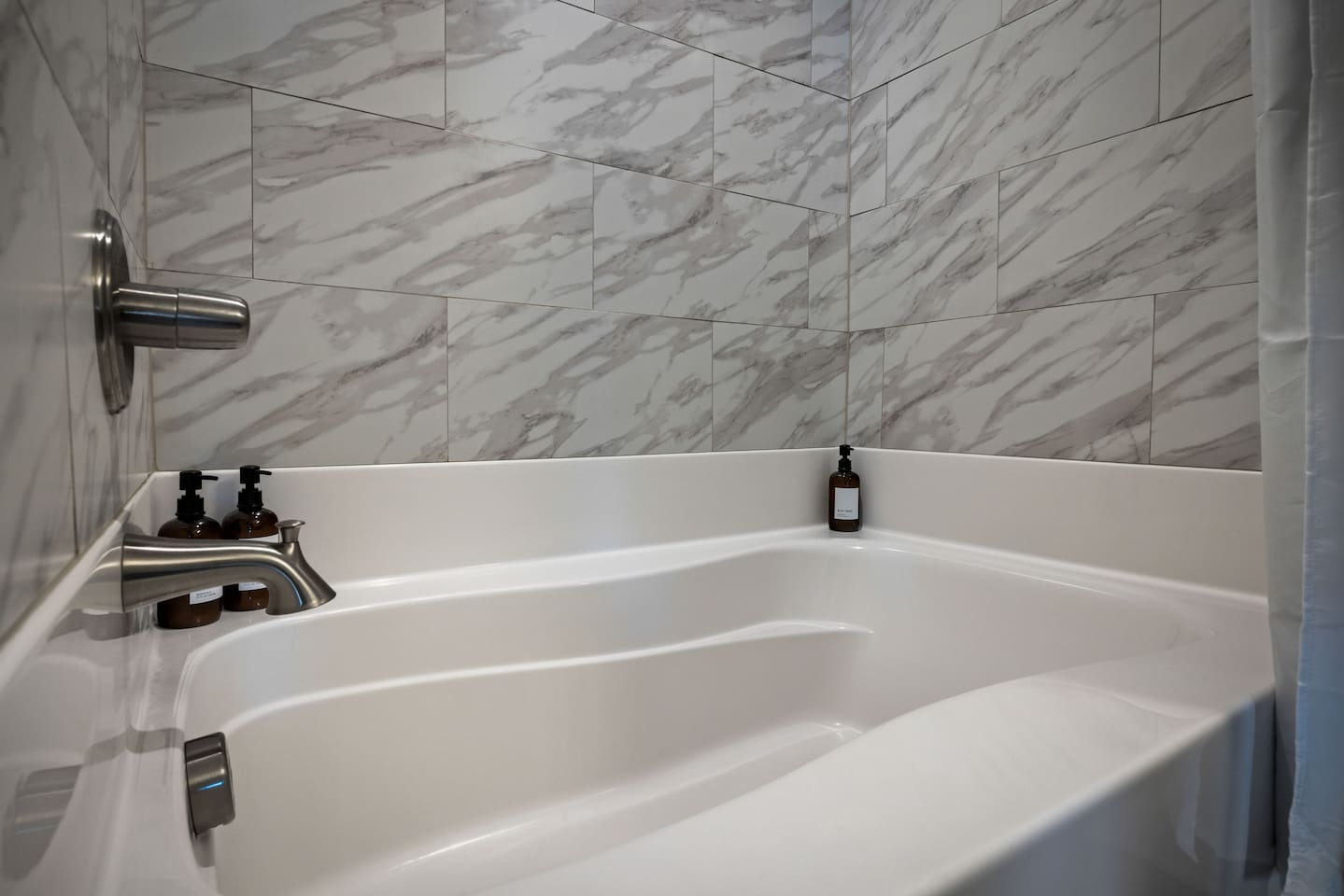 Marble-style tiles and quality bath essentials create a spa-like atmosphere.