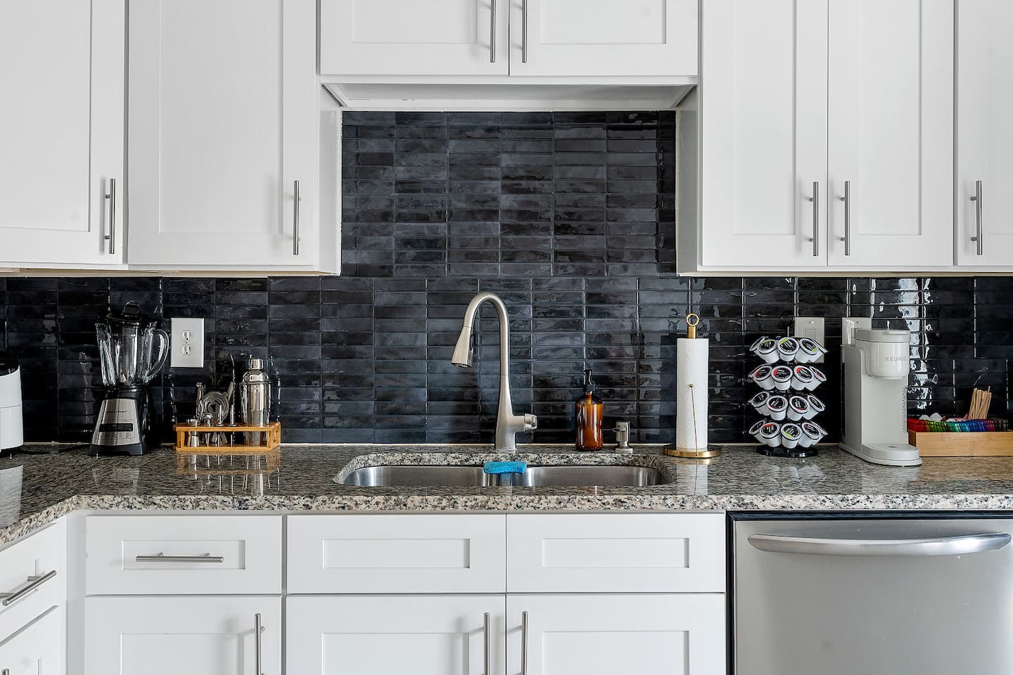 Enjoy the convenience of a fully equipped kitchen with a sleek sink area and ample counter space. The stylish backsplash complements the modern fixtures.