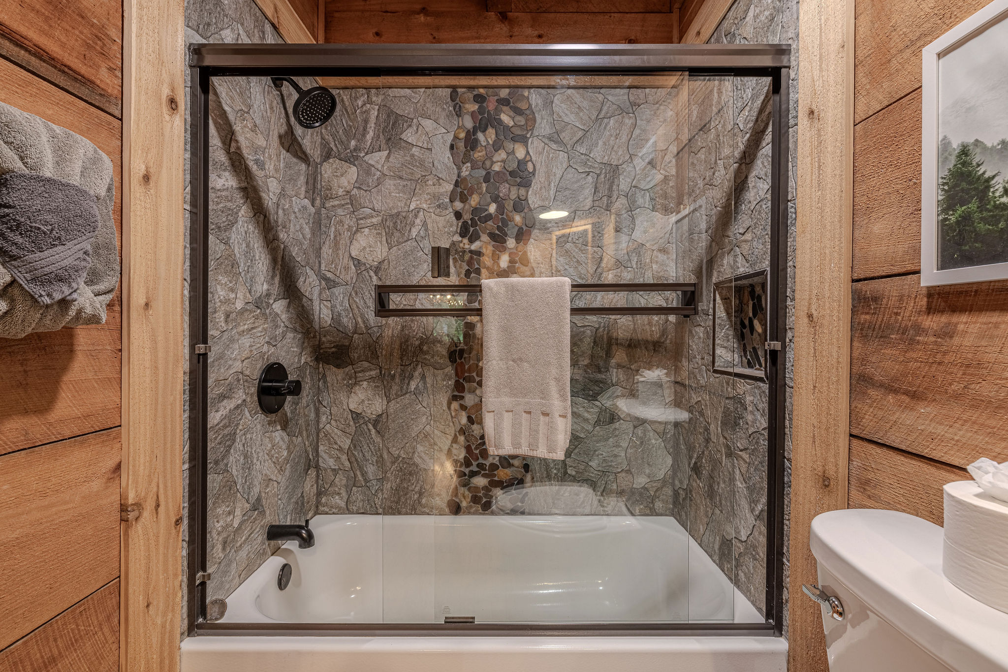 Stone shower, soaking tub, windows facing the woods.