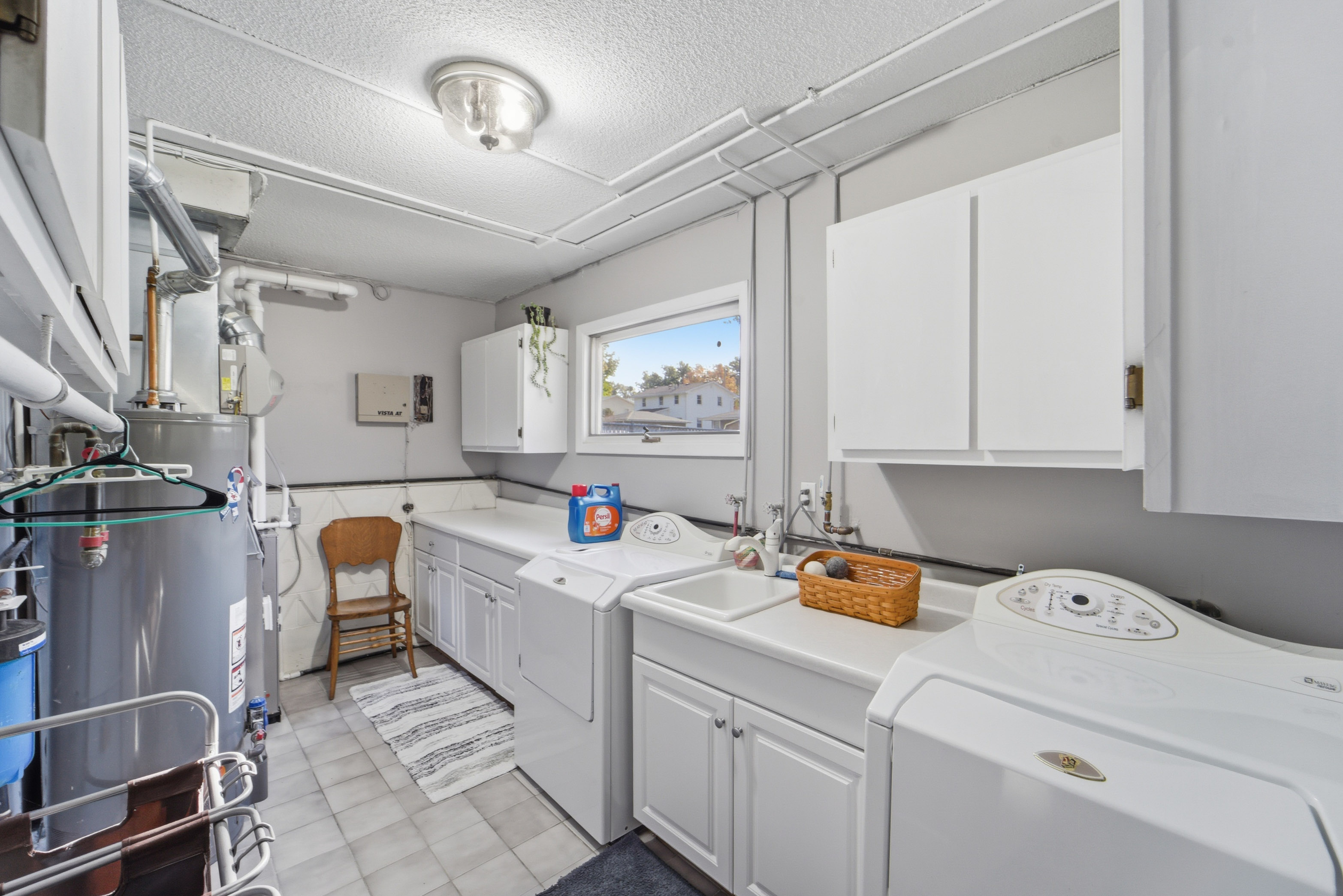 Fully stocked laundry room with front load washer and dryer, ironing board, and utility sink is located in the walk-out basement.