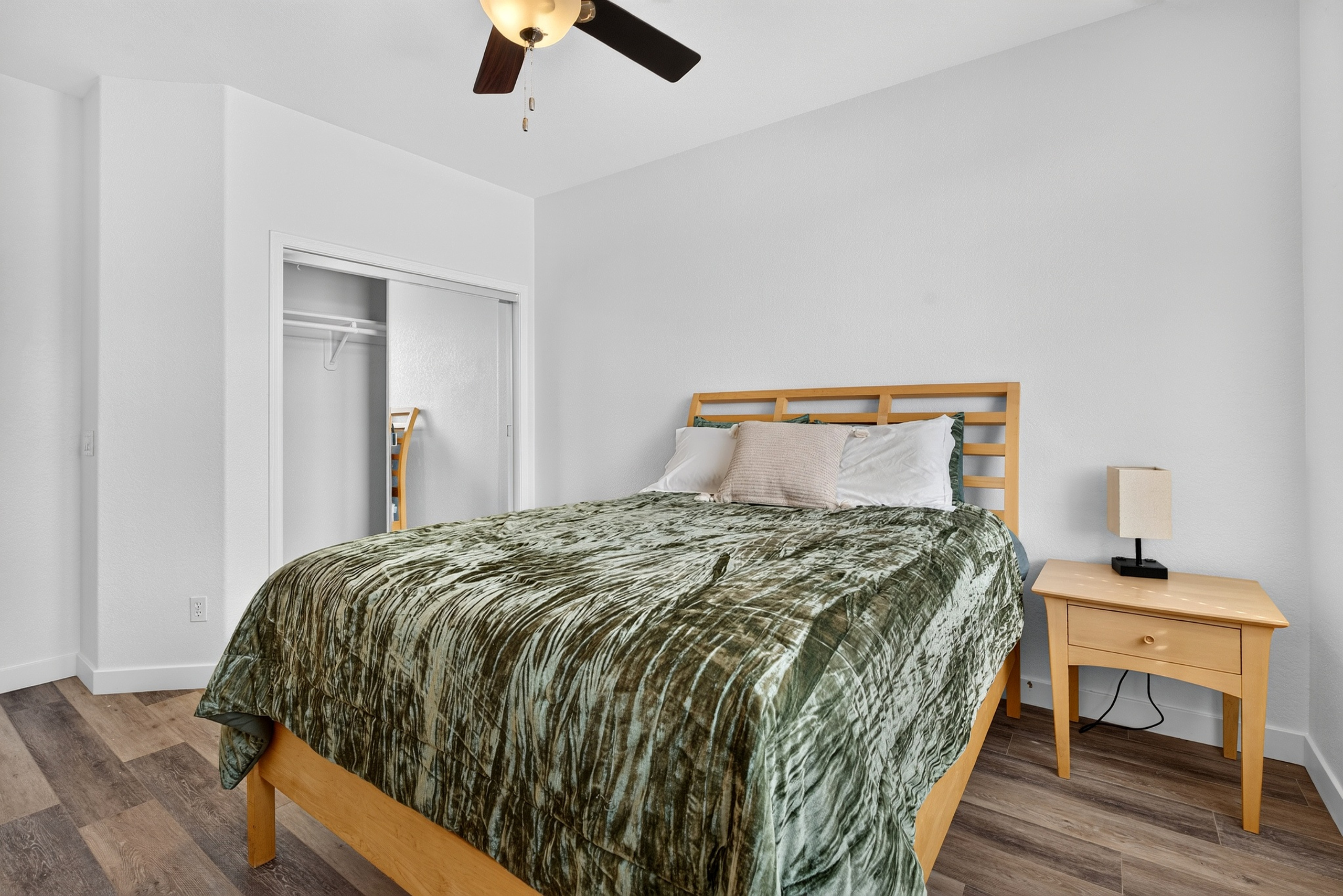 Queen bedroom with dresser storage, ceiling fan, and natural light for a comfortable stay.