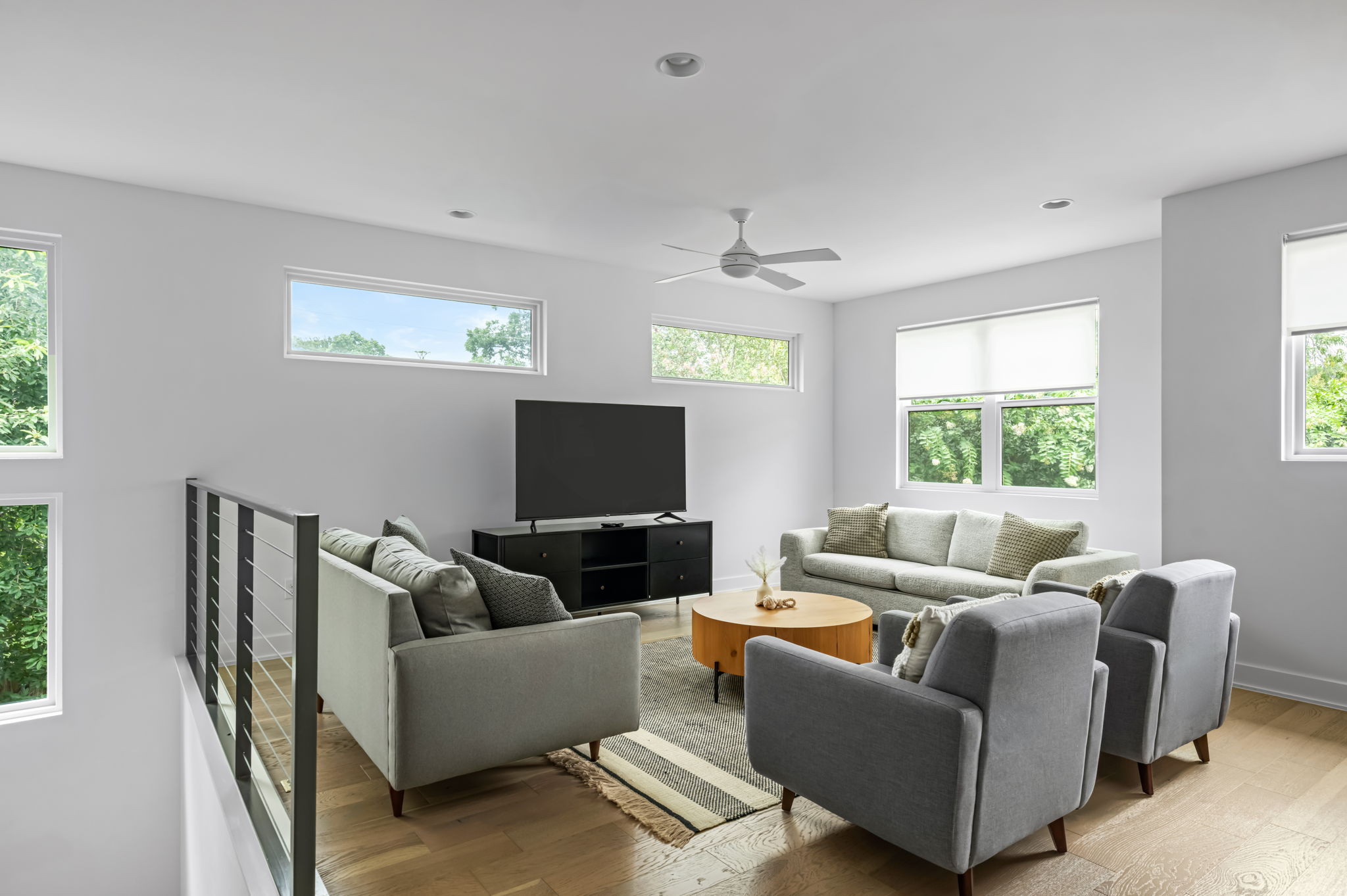 Bright loft-style living room with cozy gray sectional seating and a stylish round coffee table — a relaxed retreat for movie nights or game days.