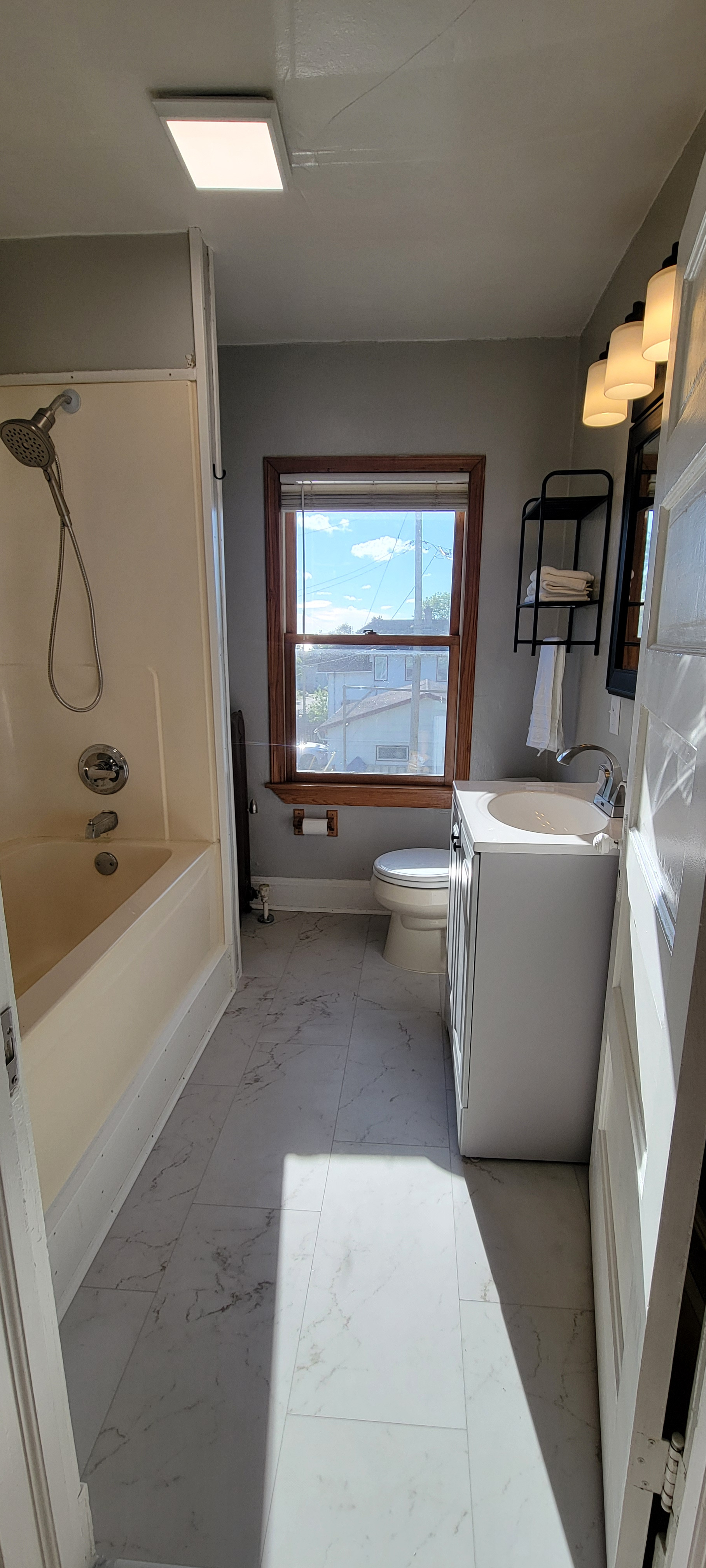 Bathroom with full tub/shower combo, sink, mirror, and fresh towels.