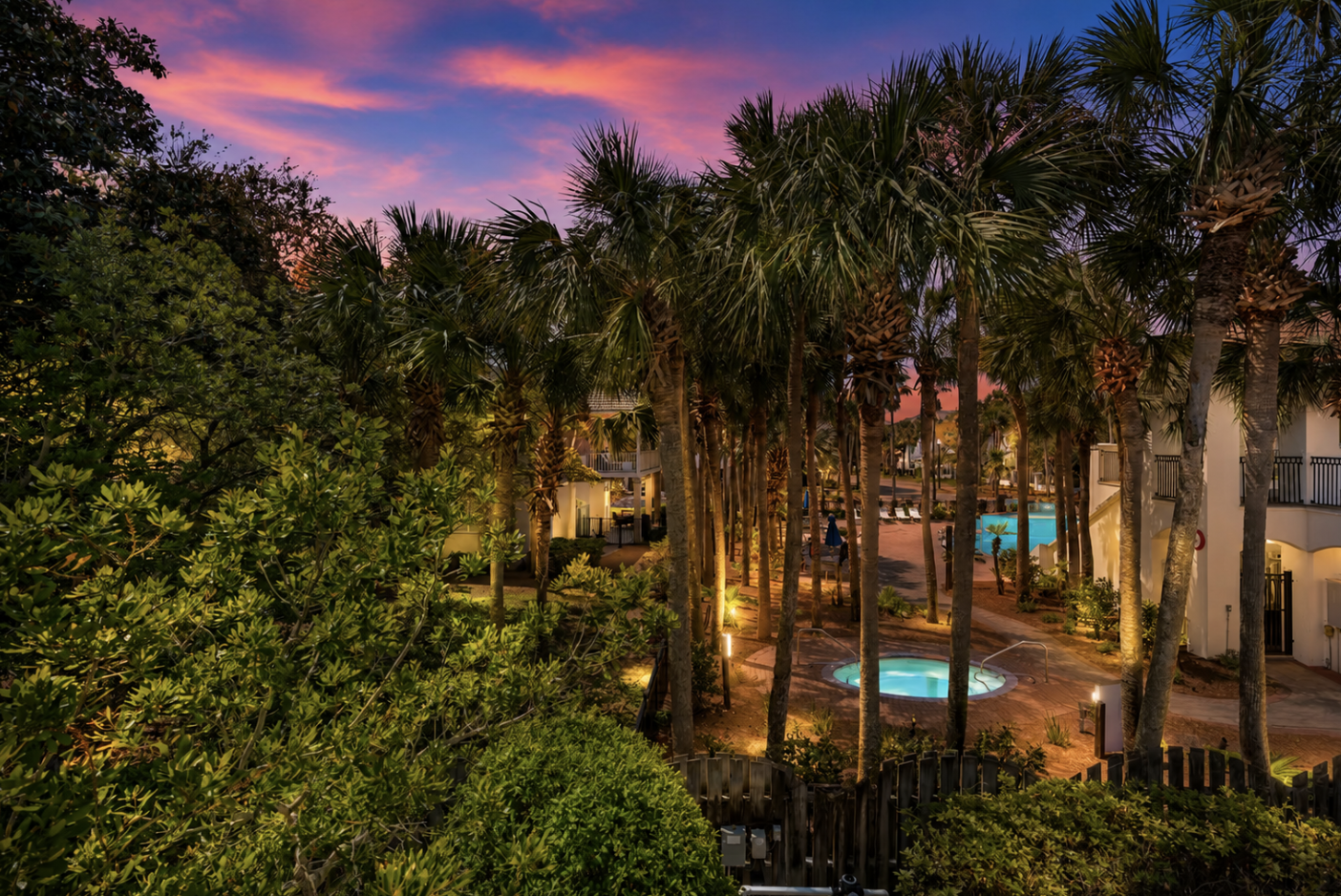 Glimpses of the community pool and hot tub among swaying palm trees from the balcony